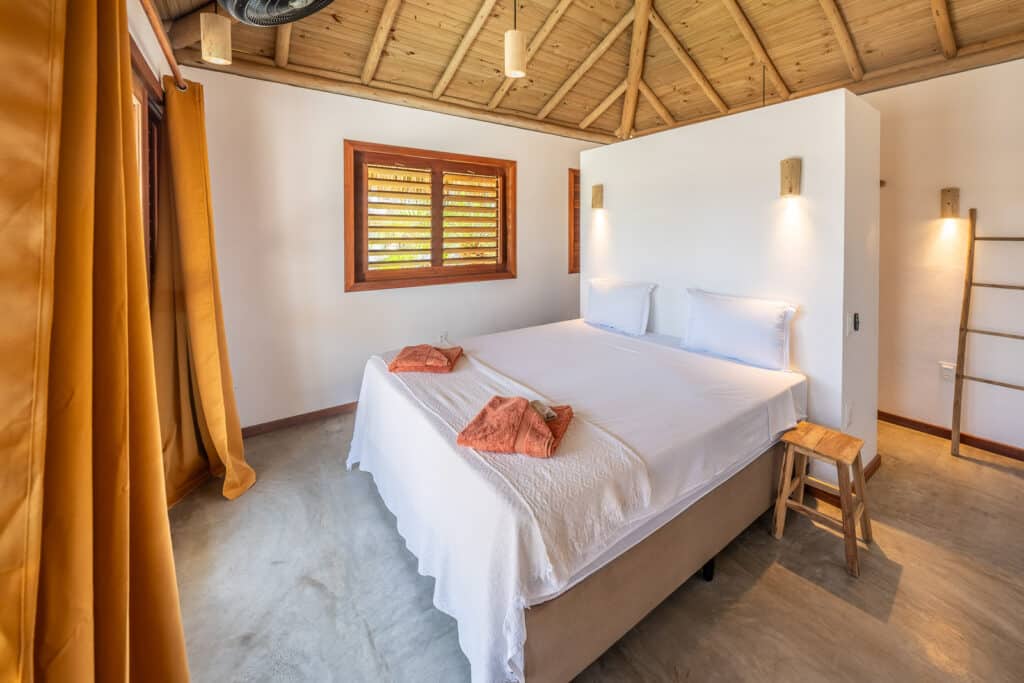 Chambre avec lit double, rideaux ocre et charpente bois apparente, La Kite Family, Fortim