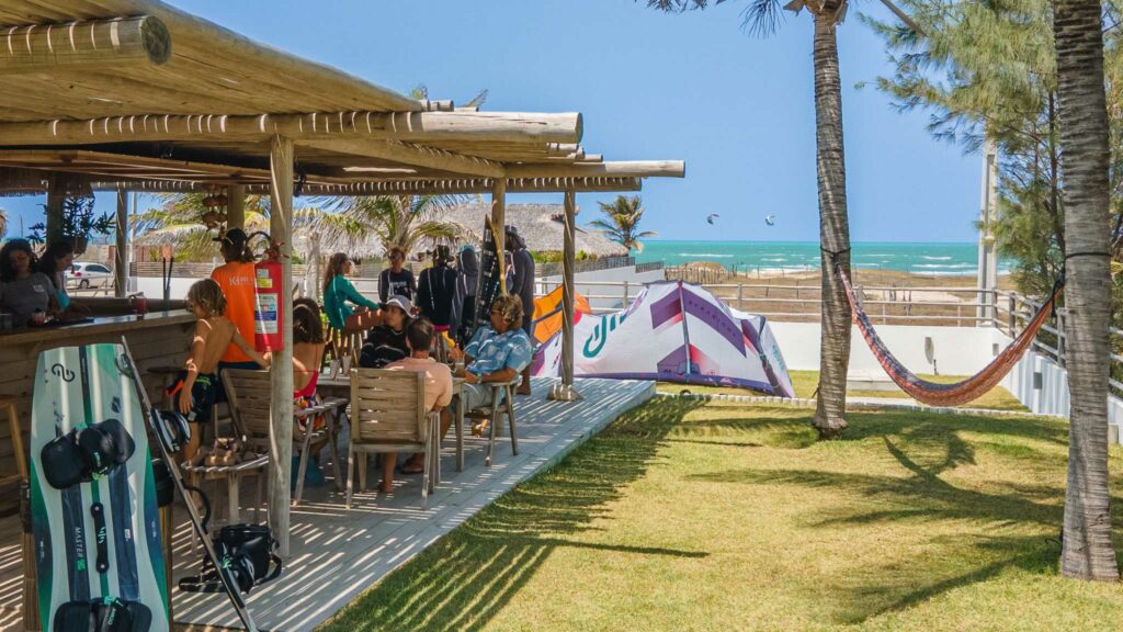 Terrasse animée du bar OLK House avec vue sur l'océan, planches de kite et hamac, Pontal de Maceió