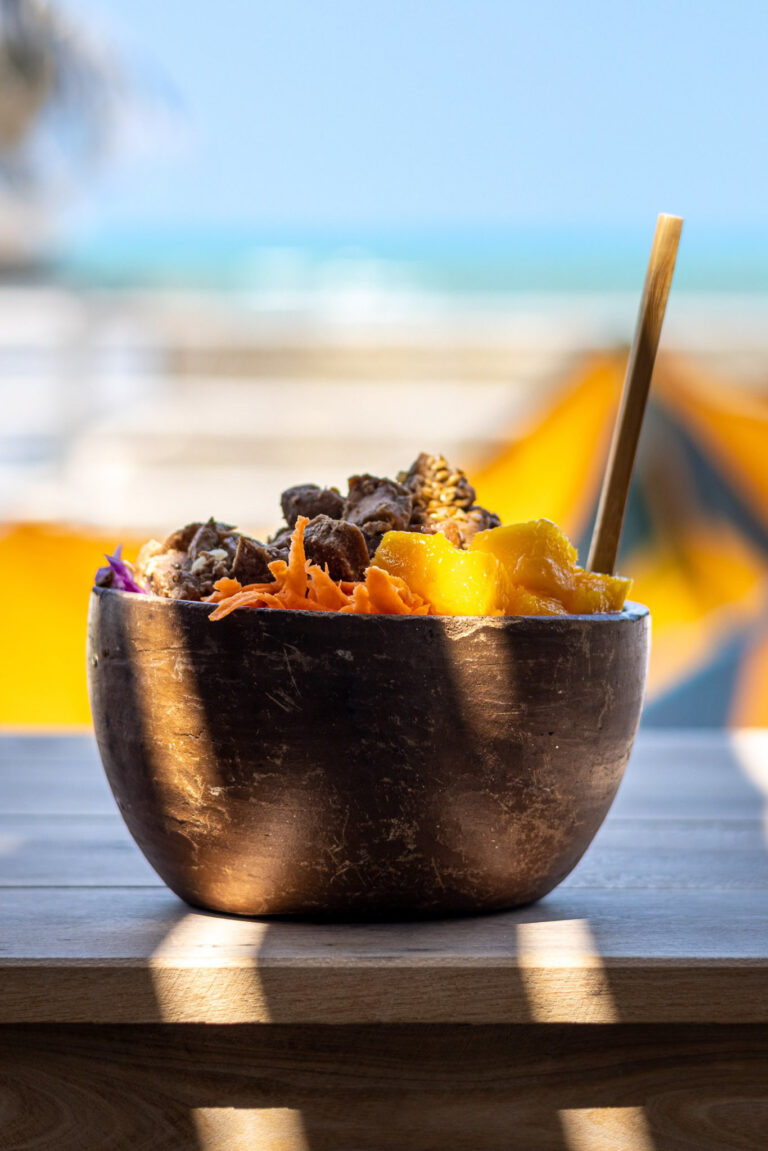 Açaí bowl garni de mangue et granola servi dans un bol en coco au bar OLK House face à la mer, Pontal de Maceió