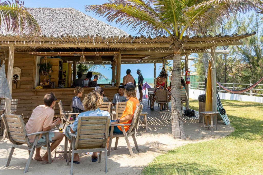 Bar en bois avec toit de palme de la OLK House, clients attablés sur le sable face à l'océan, Pontal de Maceió