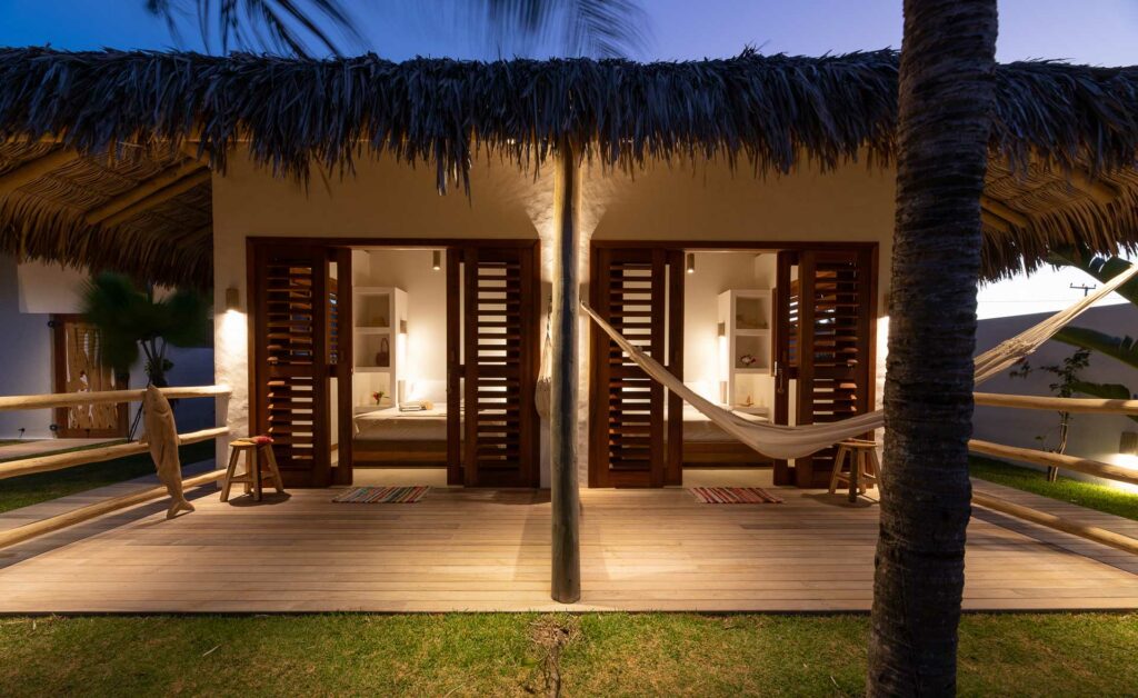 Façade de deux chambres avec portes en persiennes et hamac, ambiance nocturne à la One Launch Kite House